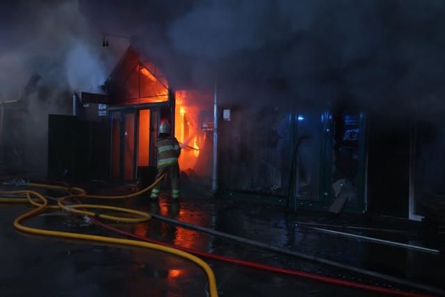 A Ukrainian rescuer uses a water hose as they work to extinguish a fire at the site of a Russian strike in Kyiv on August 16, 2026, amid the Russian invasion of Ukraine. Russian strikes killed one person and wounded at least seven others in Ukraine, authorities said August 16, while Moscow officials reported downing more than 100 drones heading towards the capital. (Photo by AFP)