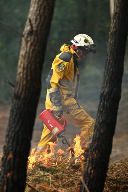 A firefighter sets a tactical fire in a forest near a farm to prevent a wildfire from spreading near Luglon, south-western France, on August 16, 2026. (Photo by Gaizka IROZ / AFP)