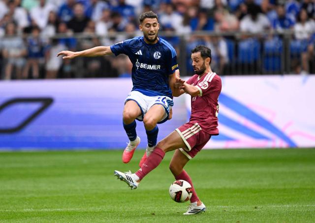 CORRECTION / Schalke's Algerian midfielder #24 Adil Aouchiche (L) and Real Madrid's Portuguese midfielder #20 Bernardo Silva vie for the ball during the pre-season friendly football match between FC Schalke 04 and Real Madrid in Gelsenkirchen, western Germany, on August 16, 2026. (Photo by INA FASSBENDER / AFP) / The erroneous mention[s] appearing in the metadata of this photo by INA FASSBENDER has been modified in AFP systems in the following manner: [Schalke's Algerian midfielder #24 Adil Aouchiche (L) and Real Madrid's Portuguese midfielder #20 Bernardo Silva] instead of [Schalke's Austrian forward #20 Junior Adamu (L) and Real Madrid's Dutch defender #24 Denzel Dumfries]. Please immediately remove the erroneous mention[s] from all your online services and delete it (them) from your servers. If you have been authorized by AFP to distribute it (them) to third parties, please ensure that the same actions are carried out by them. Failure to promptly comply with these instructions will entail liability on your part for any continued or post notification usage. Therefore we thank you very much for all your attention and prompt action. We are sorry for the inconvenience this notification may cause and remain at your disposal for any further information you may require.