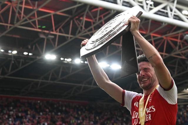 Arsenal's English midfielder #41 Declan Rice is hit in the face by the strut back as he celebrates with the trophy on the pitch after their victory in the English FA Community Shield football match between Arsenal and Manchester City at The Principality Stadium, in Cardiff, south Wales on August 16, 2026. Arsenal won the game 3-0. (Photo by Glyn KIRK / AFP)