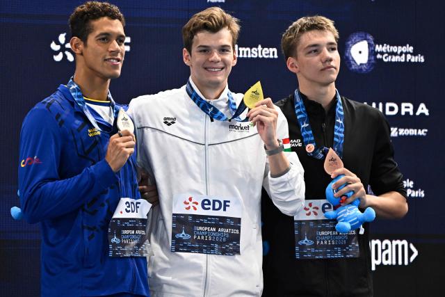 (LtoR) Spain's Hugo Gonzalez De Oliveira (silver medal), Hungary's Hubert Kos (gold medal) and Neutral athlete B Mikhail Shcherbakov (bronze medal) pose on the podium of the men's 200m individual medley swimming event during the LEN European Aquatics Championships at the Olympic Aquatic Centre in Saint-Denis, northern suburbs of Paris, on August 16, 2026. (Photo by JULIEN DE ROSA / AFP)