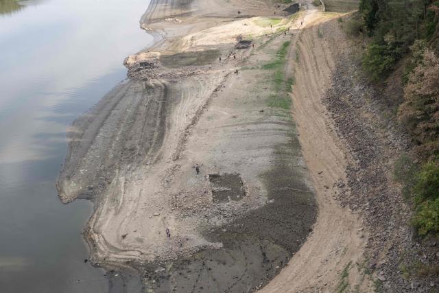 People walk on the bank of water reservoir Orlík - part of the Vltava Moldau river near Podolsko village on August 16, 2026 as water levels of the Vltava - Moldau river  have reached historic lows for almost last 65 years. (Photo by Michal Cizek / AFP)