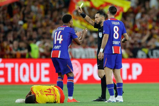 French referee Jeremie Pignard shows a yellow card to PSG's French forward #14 Desire Doue during the French Super Cup (Trophee des Champions) football match between RC Lens and Paris Saint-Germain (PSG) at the Stade Bollaert-Delelis in Lens, northern France on August 16, 2026. (Photo by GEOFFROY VAN DER HASSELT / AFP)