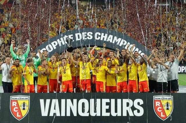 Lens' players celebrate with the championship trophy after winning the French Super Cup (Trophee des Champions) football match between RC Lens and Paris Saint-Germain (PSG) at the Stade Bollaert-Delelis in Lens, northern France on August 16, 2026. (Photo by GEOFFROY VAN DER HASSELT / AFP)