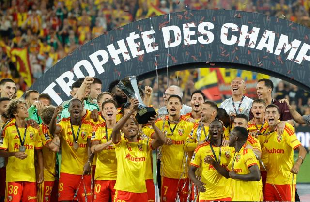 Lens' French defender #32 Kyllian Antonio holds the championship trophy as he celebrates with his teammates after winning the French Super Cup (Trophee des Champions) football match between RC Lens and Paris Saint-Germain (PSG) at the Stade Bollaert-Delelis in Lens, northern France on August 16, 2026. (Photo by GEOFFROY VAN DER HASSELT / AFP)