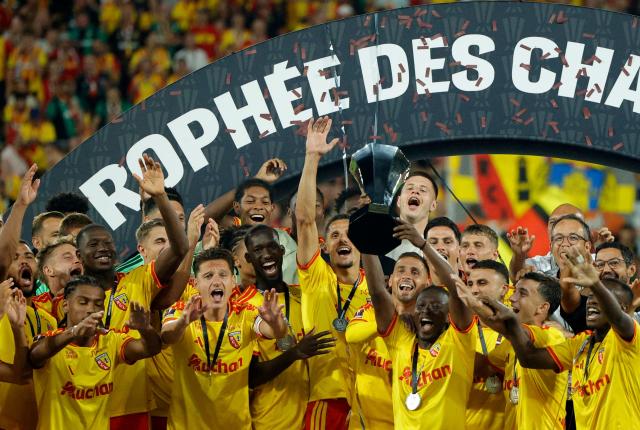 Lens' players celebrate with the championship trophy after winning the French Super Cup (Trophee des Champions) football match between RC Lens and Paris Saint-Germain (PSG) at the Stade Bollaert-Delelis in Lens, northern France on August 16, 2026. (Photo by GEOFFROY VAN DER HASSELT / AFP)