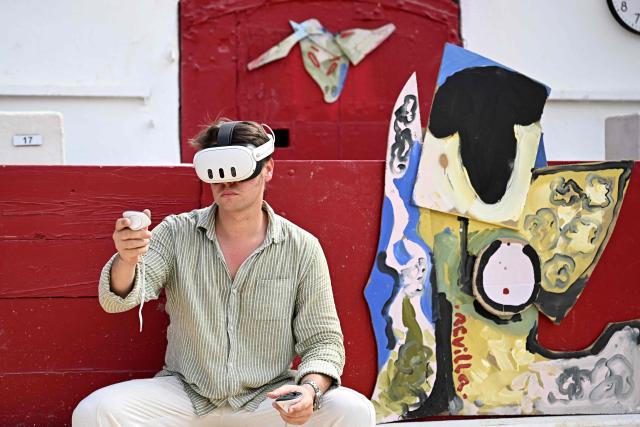 French artist Quentin Revilla uses a virtual reality headset to decorate the bullring ahead of a bullfight as part of the Feria in Beziers, southern France, on August 16, 2026. (Photo by Gabriel BOUYS / AFP)