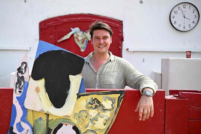 French artist Quentin Revilla poses in the bullring with original works ahead of a bullfight as part of the Feria in Beziers, southern France, on August 16, 2026. (Photo by Gabriel BOUYS / AFP)