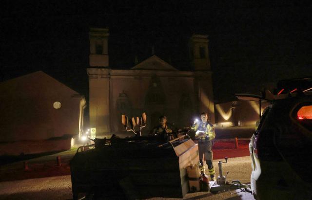 Firefighters of INFOAR Aragon forest fire prevention patrol in front of the San Juan de la Pena Monastery in Penas de Riglos, in the Spanish northeastern province of Aragon amid a wildfire that burnt 16,600 hectares on August 16, 2026. A Spanish soldier died on August 16, 2026 while helping efforts to extinguish a major wildfire in the northeastern region of Aragon that has raged for a week and threatened a 1,000-year-old monastery. Regional authorities said more than 16,600 hectares had been affected and around 1,000 people evacuated from various small settlements and villages. (Photo by Oscar DEL POZO / AFP)