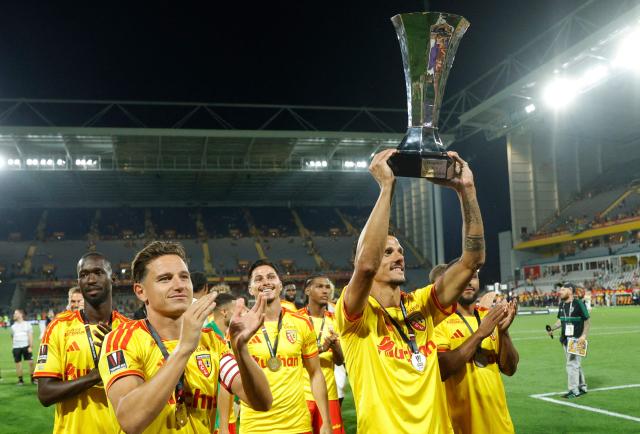 Lens' French forward #07 Florian Sotoca holds the championship trophy as he celebrates with his teammates after winning the French Super Cup (Trophee des Champions) football match between RC Lens and Paris Saint-Germain (PSG) at the Stade Bollaert-Delelis in Lens, northern France on August 16, 2026. (Photo by GEOFFROY VAN DER HASSELT / AFP)