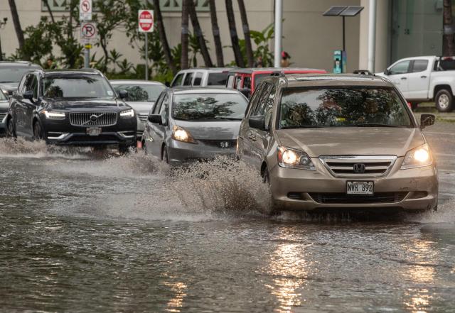 Vehicles make their way through a flooded intersection in front of the Hawaii Convention Center in Honolulu, Hawaii, on August 16, 2026. Hurricane Lala was pulling away from Hawaii's Big Island early Sunday, as heavy rain and strong winds struck the US Pacific state and officials warned of potentially dangerous flooding. The heavy rain and flood risk will then spread westward across the island chain on Sunday, according to the NHC. (Photo by Eugene Tanner / AFP)