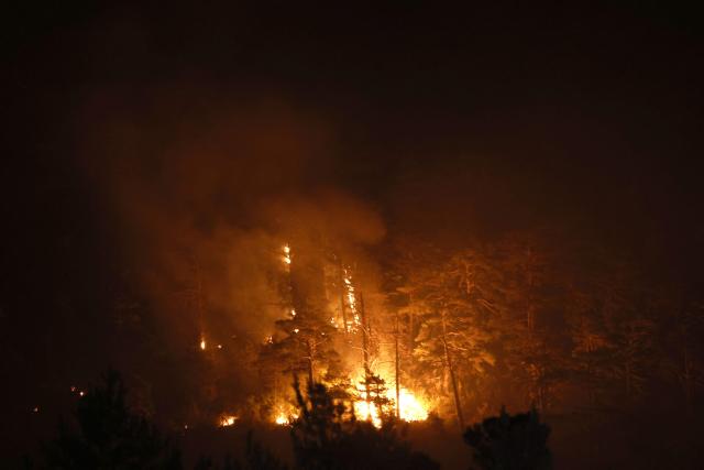 Burning trees are pictured as firefighters battle fire in Santa Cruz de la Seros in the Spanish northeastern province of Aragon, in the night of August 16-17, 2026 amid a wildfire that burnt 16,600 hectares. A Spanish soldier died on August 16, 2026 while helping efforts to extinguish a major wildfire in the northeastern region of Aragon that has raged for a week and threatened a 1,000-year-old monastery. Regional authorities said more than 16,600 hectares had been affected and around 1,000 people evacuated from various small settlements and villages. (Photo by Oscar DEL POZO / AFP)