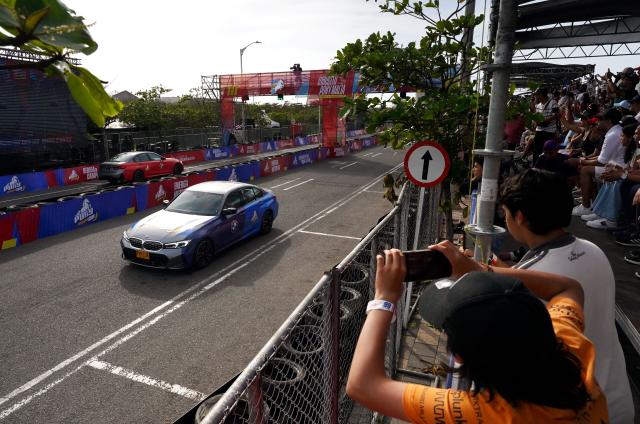 Patrons take pictures during a racing event with Colombian Formula 1 driver Juan Pablo Montoya and his son Sebastian, which profit will be donated to the recent 7.4 earthquake victims, on a street circuit in Barranquilla, Colombia on August 16, 2026. At least 287 people have died, thousands have been injured and about 379 remain unaccounted for, as the chances of finding earthquake survivors have dropped sharply since the critical 72-hour window passed, though volunteers and rescue crews continue digging through the rubble for any signs of life. (Photo by Vanexa Romero / AFP)