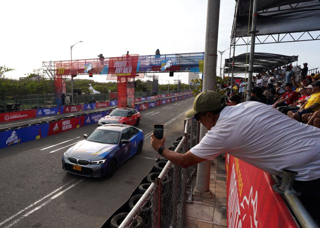 Patrons take pictures during a racing event with Colombian Formula 1 driver Juan Pablo Montoya and his son Sebastian, which profit will be donated to the recent 7.4 earthquake victims, on a street circuit in Barranquilla, Colombia on August 16, 2026. At least 287 people have died, thousands have been injured and about 379 remain unaccounted for, as the chances of finding earthquake survivors have dropped sharply since the critical 72-hour window passed, though volunteers and rescue crews continue digging through the rubble for any signs of life. (Photo by Vanexa Romero / AFP)
