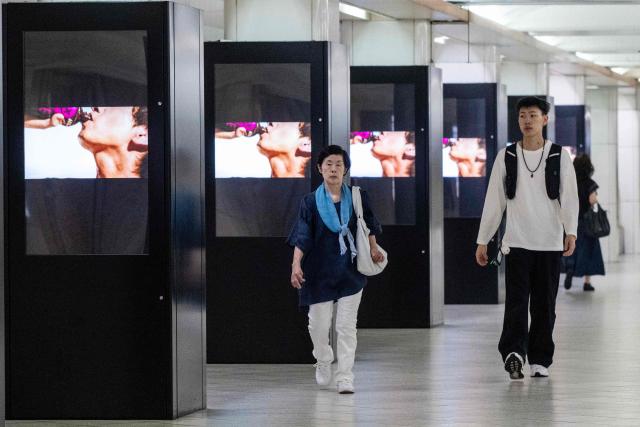Commuters walk past advertising panels for a soft drink in the metro station in Tokyo's Itabashi ward on August 17, 2026. Japanese economic growth showed a surprise slowdown in the second quarter, official data showed, as capital expenditure dropped along with consumption. (Photo by Andrew CABALLERO-REYNOLDS / AFP)