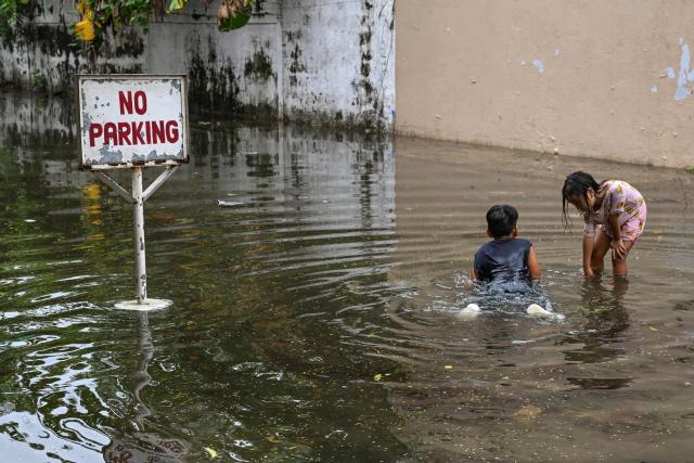 Children play in a flooded street due to the rains brought by the southwest monsoon in Manila on August 17, 2026. (Photo by Jam STA ROSA / AFP)