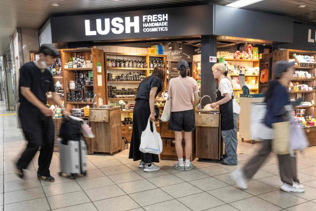 Customers look at products at a Lush store, as commuters walk past in the metro in Tokyo's Itabashi ward on August 17, 2026. Japanese economic growth showed a surprise slowdown in the second quarter, official data showed, as capital expenditure dropped along with consumption. (Photo by Andrew CABALLERO-REYNOLDS / AFP)