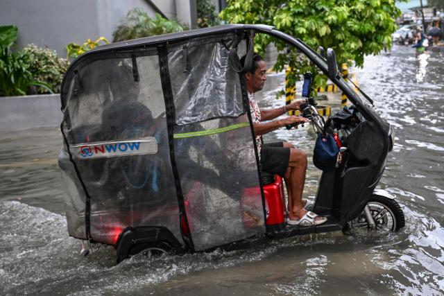 A man drives an electric vehicle through a flooded street due to the rains brought by the southwest monsoon in Manila on August 17, 2026. (Photo by Jam STA ROSA / AFP)