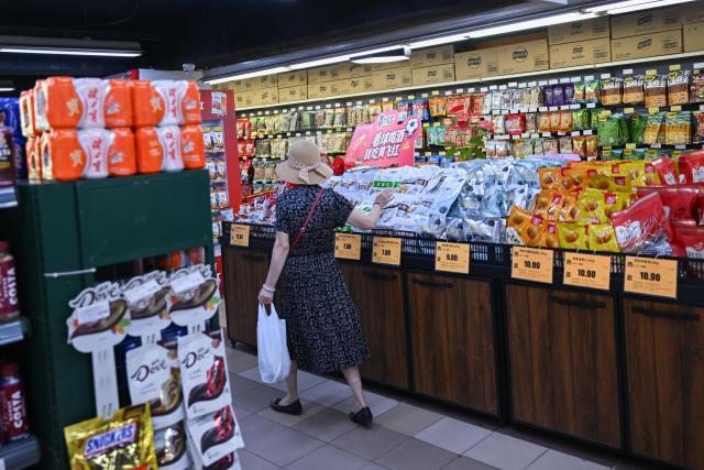 A customer selects a product at a supermarket in Beijing on August 17, 2026. (Photo by Pedro PARDO / AFP)
