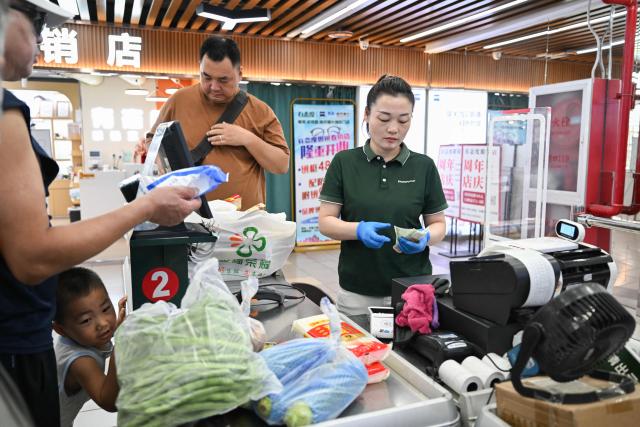 A cashier rings up a purchase at a supermarket in Beijing on August 17, 2026. (Photo by Pedro PARDO / AFP)