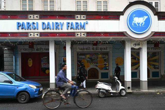 This photograph taken on August 1, 2026 shows a cyclist riding past the 110 year-old Parsi Dairy Farm which reopened after being closed down for food safety norms violation by Maharashtra's Food and Drug Administration (FDA) in Mumbai. When food safety inspectors raided a Mumbai dessert parlour famed for its ice cream sandwiches last month, they found rats, houseflies and expired flavouring agents. At another beloved restaurant known for slow-cooked mutton and beef stews, they discovered meat stored in filthy containers, greasy floors and open windows that could let in insects and crows. Both eateries were ordered shut in the toughest crackdown in years on restaurants in the megacity of more than 20 million people. The sweep has targeted everything from top eateries and luxury hotels to canteens at elite institutions, including the nearly century-old Cricket Club of India. (Photo by Indranil Mukherjee / AFP)