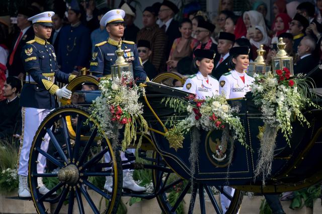 Two school students (R) ride in a royal carriage carrying the heritage flag before a flag raising ceremony marking Indonesia's 81st Independence Day at Merdeka Palace in Jakarta on August 17, 2026. (Photo by BAY ISMOYO / AFP)