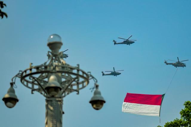 A helicopter carrying a giant Indonesian flag flies past during a ceremony marking Indonesia's 81st Independence Day at Merdeka Palace in Jakarta on August 17, 2026. (Photo by BAY ISMOYO / AFP)