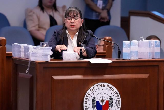 Former Office of the Vice President special disbursing officer Gina Acosta is surrounded by mock money presented during the impeachment trial of Philippine Vice President Sara Duterte at the Senate in Pasay city, Metro Manila on August 17, 2026. (Photo by Aaron Favila / POOL / AFP)
