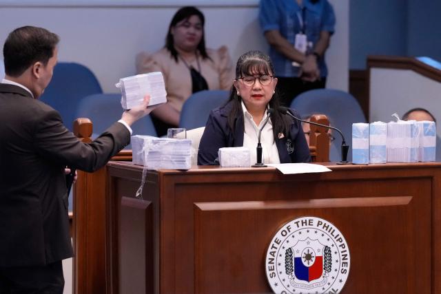 Former Office of the Vice President special disbursing officer Gina Acosta (R) is surrounded by mock money presented during the impeachment trial of Philippine Vice President Sara Duterte at the Senate in Pasay city, Metro Manila on August 17, 2026. (Photo by Aaron Favila / POOL / AFP)