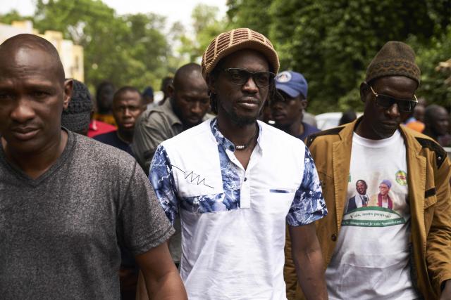(FILES) Malian activist Ras Bath (C) arrives to attend a press conference organised by opposition parties in Bamako's Maison de la Presse (press house) on August 1, 2018. A Malian court sentenced on Monday a prominent journalist and an influencer, who had both criticised the ruling junta, to seven years in jail, an AFP journalist saw. 
Television and radio commentator Mohamed Youssouf Bathily -- alias Ras Bath -- was convicted by the court in Bamako of criminal conspiracy and discrediting the state, alongside Rokia Doumbia, a noted campaigner known online as "Rose, the cost of living". (Photo by Michele CATTANI / AFP)