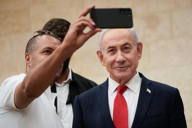 Israeli Prime Minister Benjamin Netanyahu, takes a selfie with a supporter as he arrives to cast his ballot at his party Likud's main polling station during primary elections ahead of Israels general election in October in Jerusalem on August 17, 2026. The Likud, the historic party of the Israeli right and the political base of Prime Minister Benjamin Netanyahu, held primaries on August 17 to determine its slate of candidates for the general election on October 27. Likud is projected to win around 22-23 of the 120 seats in the Knesset, Israel's parliament, according to the latest polls -- a dramatic drop from the 32 seats it won in the 2022 election. (Photo by Ohad Zwigenberg / POOL / AFP)