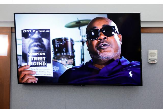 A photo of Duane Davis holding his book "Compton Street Legend" is displayed during opening statements of his murder trial, related to the 1996 killing of rapper Tupac Shakur, at Clark County District Court in the Regional Justice Center in Las Vegas, Nevada, on August 17, 2026. The trial of the former gang leader accused of orchestrating the murder of rapper Tupac Shakur began on August 10, 30 years after one of America's most high-profile unresolved killings. The proceedings, expected to last a month, will likely not make clear who fired the shots that killed the California hip-hop legend on the night of September 7, 1996, while he was in Las Vegas to see a Mike Tyson boxing match. (Photo by STEVE MARCUS / POOL / AFP)