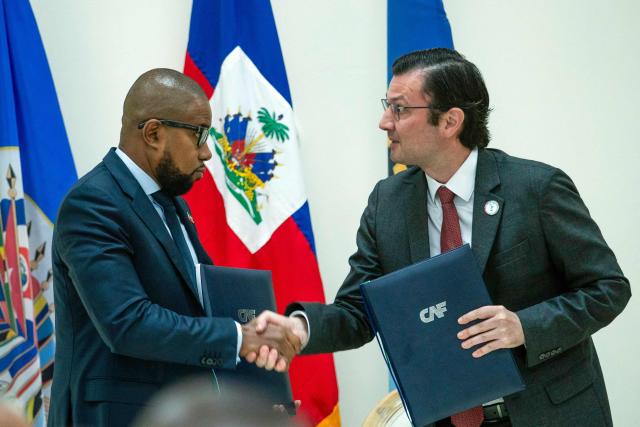 Haiti's Minister of Economy and Finance Serge Gabriel Colin (L) shakes hands with the Executive Vice President of CAF-Development Bank of Latin America and the Caribbean Gianpiero Leonini after signing an agreement intended to allow Haiti to strengthen its cooperation with the financial institution and access new financing opportunities during an event at the National Palace in Port-au-Prince, Haiti, on August 17, 2026. (Photo by Clarens SIFFROY / AFP)