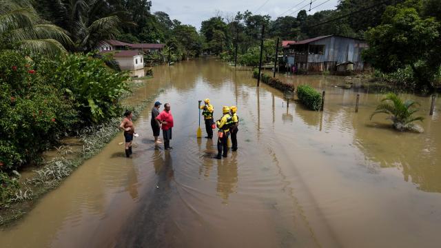 Firefighters talk to local residents amid flooded waters following heavy rains in Puerto Viejo de Sarapique, Heredia province, Costa Rica, on August 17, 2026. (Photo by ALONSO TENORIO / AFP)
