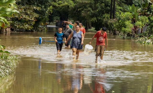Locals walk through flooded waters following heavy rains in Puerto Viejo de Sarapique, Heredia province, Costa Rica, on August 17, 2026. (Photo by ALONSO TENORIO / AFP)