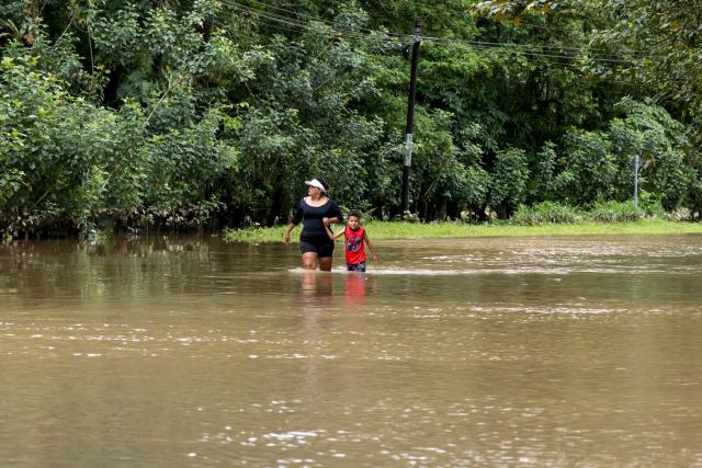 Locals walk through flooded waters following heavy rains in Puerto Viejo de Sarapique, Heredia province, Costa Rica, on August 17, 2026. (Photo by ALONSO TENORIO / AFP)