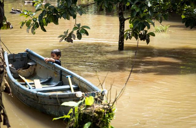 A boy hangs from a boat in flooded waters following heavy rains in Puerto Viejo de Sarapique, Heredia province, Costa Rica, on August 17, 2026. (Photo by ALONSO TENORIO / AFP)