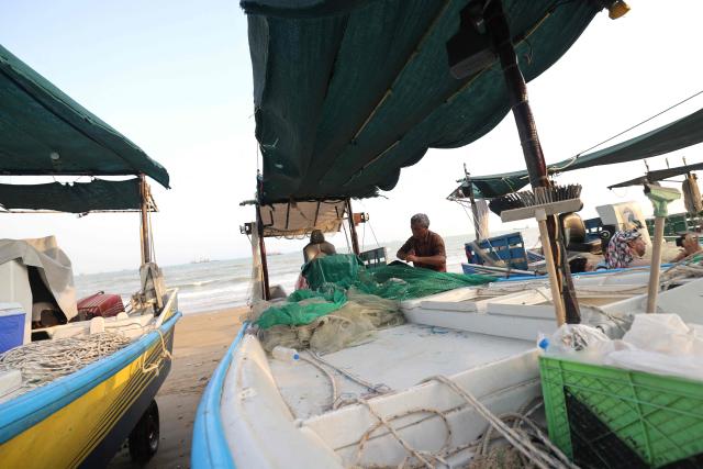 (FILES) Fishermen check their nets and small boats on the seashore in the port city of Bandar Abbas, in southern Iran on August 10, 2026. On his boat along the Strait of Hormuz, Iranian fisherman Mohammad-Amin mended a torn fishing net after a long day in waters that had sustained his livelihood for years but now carry debris of war and the threat of death. The 47-year-old only resumed his routine of waking before dawn, heading out to sea and returning hours later with the day's catch less than a month ago, after months of fighting between Iran and the United States in and around the strategic waterway eased. (Photo by Atta KENARE / AFP) / 