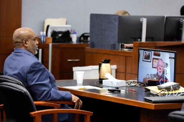 Duane Davis watches as Brent Becker, a retired Las Vegas Metro Police Department homicide detective, testifies by video feed during his murder trial, related to the 1996 killing of rapper Tupac Shakur, at Clark County District Court at the Regional Justice Center in Las Vegas, Nevada, on August 17, 2026. The trial of the former gang leader accused of orchestrating the murder of rapper Tupac Shakur began on August 10, 30 years after one of America's most high-profile unresolved killings. The proceedings, expected to last a month, will likely not make clear who fired the shots that killed the California hip-hop legend on the night of September 7, 1996, while he was in Las Vegas to see a Mike Tyson boxing match. (Photo by Steve Marcus / POOL / AFP)