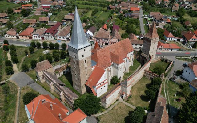 An aerial view of the fortified church in the village of Mosna, Romania, on August 7, 2026. Built in the late Middle Ages to provide shelter from attacks, Transylvania's famous fortified churches risk crumbling despite efforts to preserve and breathe new life into them. Transylvania region holds over 160 fortified churches, built by the German minority so that the population could take refuge behind the defensive walls, as the region was a disputed border territory. As the Saxons left Romania, many to escape the communist dictatorship of Nicolae Ceausescu, several of the churches started to deteriorate with no one left to look after them. They are among historic monuments and other buildings in the eastern European country -- one of the poorest in the EU -- to fall victim to neglect and face decay. (Photo by Daniel MIHAILESCU / AFP)