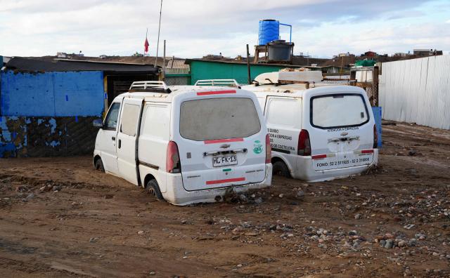 Two vans are pictured in the mud at fishermen's cove after a mudslide following heavy rains in Puerto Viejo, Caldera commune, Atacama region, Chile on August 17, 2026. (Photo by Patricio BANDA / AFP)