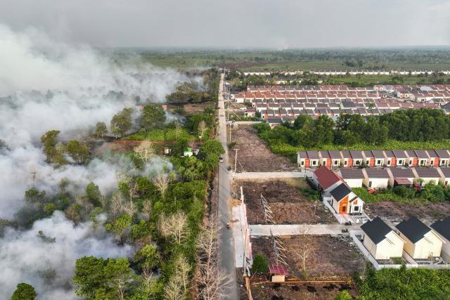 This aerial picture taken on July 19, 2026 shows smoke rising from a wildfire next to housing complex in Kubu Raya, West Kalimantan. Indonesia believes cloud seeding can help it tackle a wildfire season that experts say is on track to be among the worst in years, driven by a strong El Nino. (Photo by DITO / AFP)
