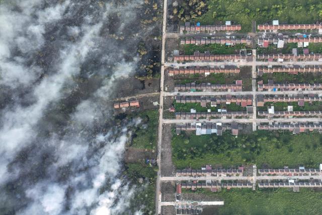 This aerial picture taken on July 19, 2026 shows smoke rising from a wildfire next to housing complex in Kubu Raya, West Kalimantan. Indonesia believes cloud seeding can help it tackle a wildfire season that experts say is on track to be among the worst in years, driven by a strong El Nino. (Photo by DITO / AFP)