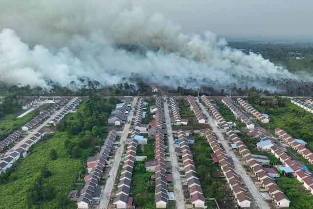 TOPSHOT - This aerial picture taken on July 19, 2026 shows smoke rising from a wildfire next to housing complex in Kubu Raya, West Kalimantan. Indonesia believes cloud seeding can help it tackle a wildfire season that experts say is on track to be among the worst in years, driven by a strong El Nino. (Photo by DITO / AFP)