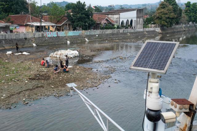 This picture taken on August 6, 2026 shows villagers collecting dirt on rocks surfacing at the bottom of a river as the water level drops in part due to the impact of El Nino, at Katulampa floodgate in Bogor, West Java. Indonesia believes cloud seeding can help it tackle a wildfire season that experts say is on track to be among the worst in years, driven by a strong El Nino. (Photo by BAY ISMOYO / AFP)