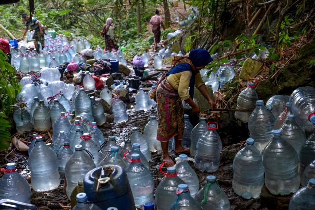 (FILES) Villagers collect spring water with bottles at Gunung Batur village in Cilegon, Banten province, on July 17, 2026, after struggling to access groundwater at their homes in part due to the impact of El Nino, which has brought a prolonged dry season and triggered extreme drought, threatening food security in various regions of Indonesia. Indonesia believes cloud seeding can help it tackle a wildfire season that experts say is on track to be among the worst in years, driven by a strong El Nino. (Photo by BAY ISMOYO / AFP)