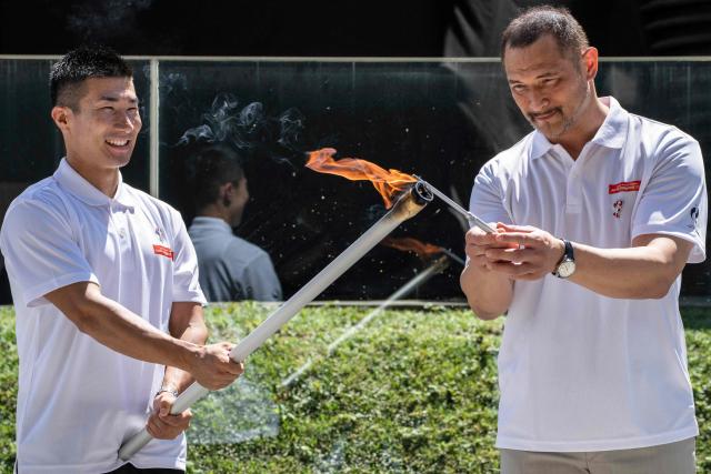 Japanese sprinter Yoshihide Kiryu (L) and former hammer throw athlete Koji Murofushi take part in the torch lighting ceremony for the 2026 Asian Games, outside the National Stadium in Tokyo on August 18, 2026. About 15,000 competitors and officials are expected at the event, which takes place in Nagoya and the wider Aichi area from September 19 to October 4. (Photo by Yuichi YAMAZAKI / AFP)