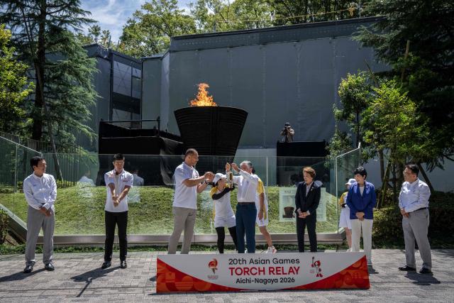 Participants take part in the torch lighting ceremony for the 2026 Asian Games, outside the National Stadium in Tokyo on August 18, 2026. About 15,000 competitors and officials are expected at the event, which takes place in Nagoya and the wider Aichi area from September 19 to October 4. (Photo by Yuichi YAMAZAKI / AFP)