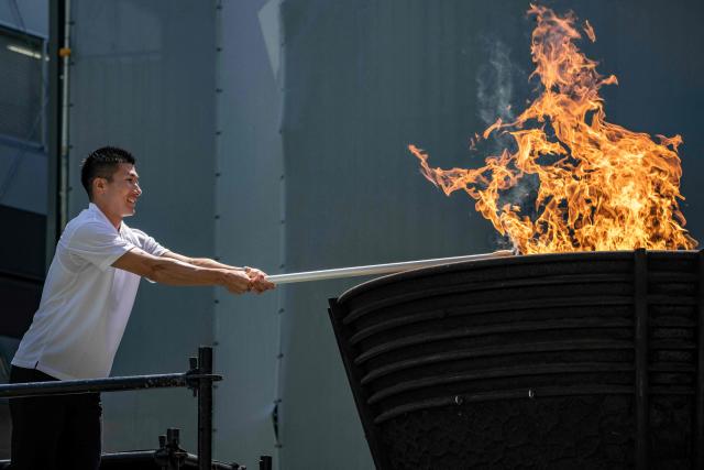 Japanese sprinter Yoshihide Kiryu lights the torch from the Olympic cauldron during the torch lighting ceremony for the 2026 Asian Games, outside the National Stadium in Tokyo on August 18, 2026. About 15,000 competitors and officials are expected at the event, which takes place in Nagoya and the wider Aichi area from September 19 to October 4. (Photo by Yuichi YAMAZAKI / AFP)