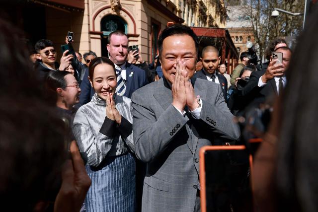 Thailand's Prime Minister Anutin Charnvirakul (C) and his wife Thananon Niramit (L) react to members of the public as they visit Thaitown in Sydney on August 18, 2026. The Thai Prime Minister is on a three-day official visit to Australia. (Photo by DAVID GRAY / AFP)
